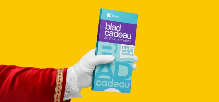 Hand van Sinterklaas tegen een gele achtergrond met een Bladcadeau in de hand