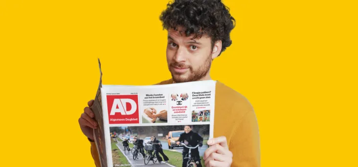 Blauwe achtergrond met man die het AD in zijn handen heeft